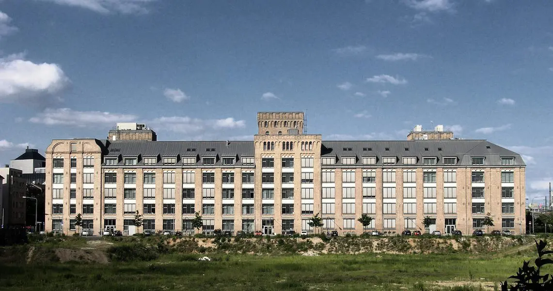 Adlerwerke in Frankfurt, langgestrecktes historisches Gebäude mit Wiese davor
