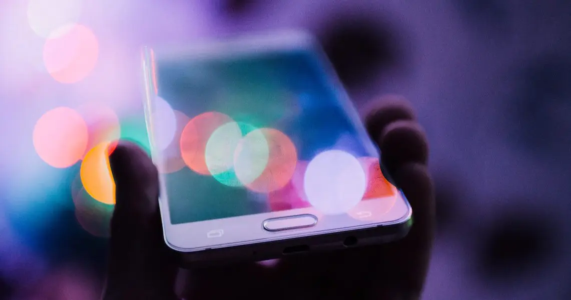 smartphone Hand hält ein Smartphone mit bunten Lichtreflexen